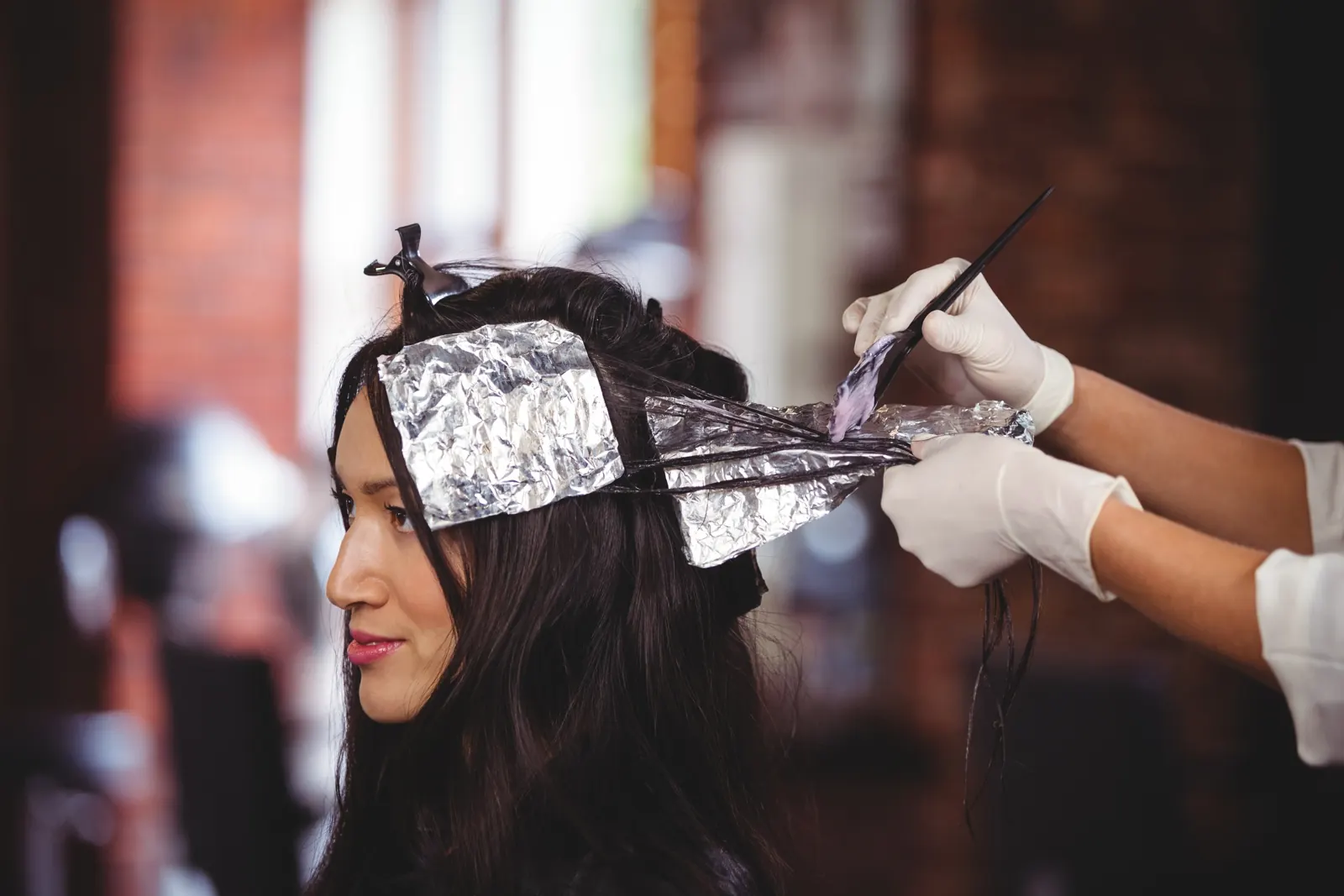 Colorista aplicando mechas con papel aluminio