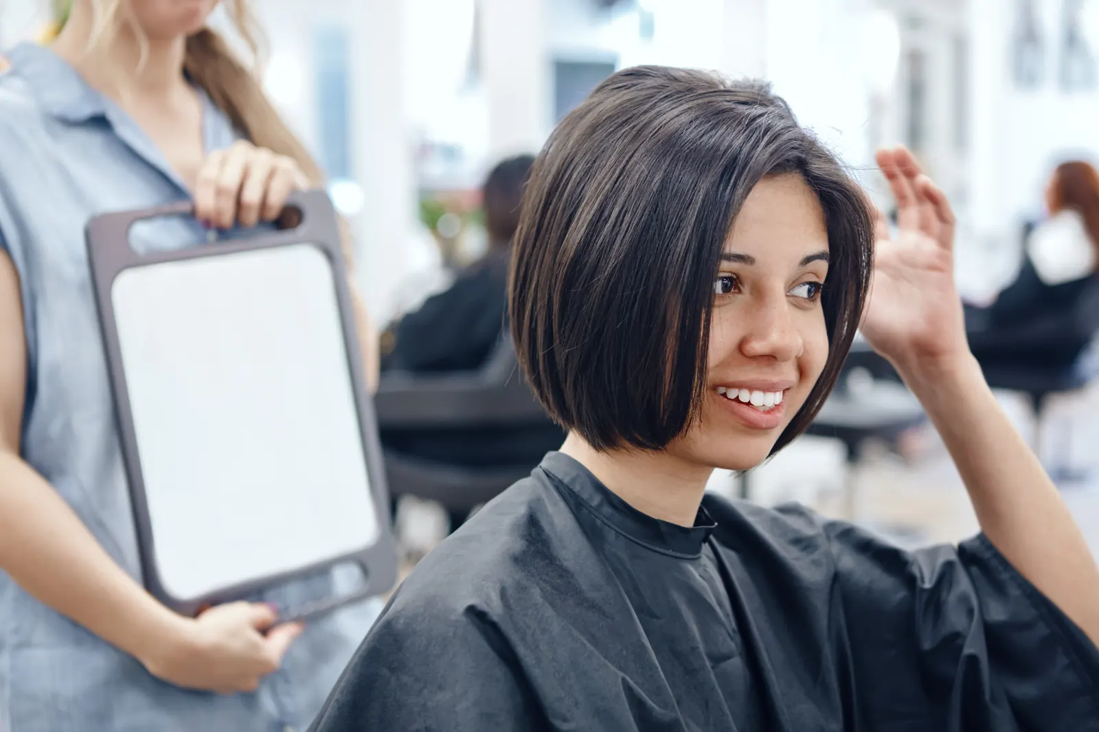 Clienta sonriendo frente al espejo con su corte nuevo